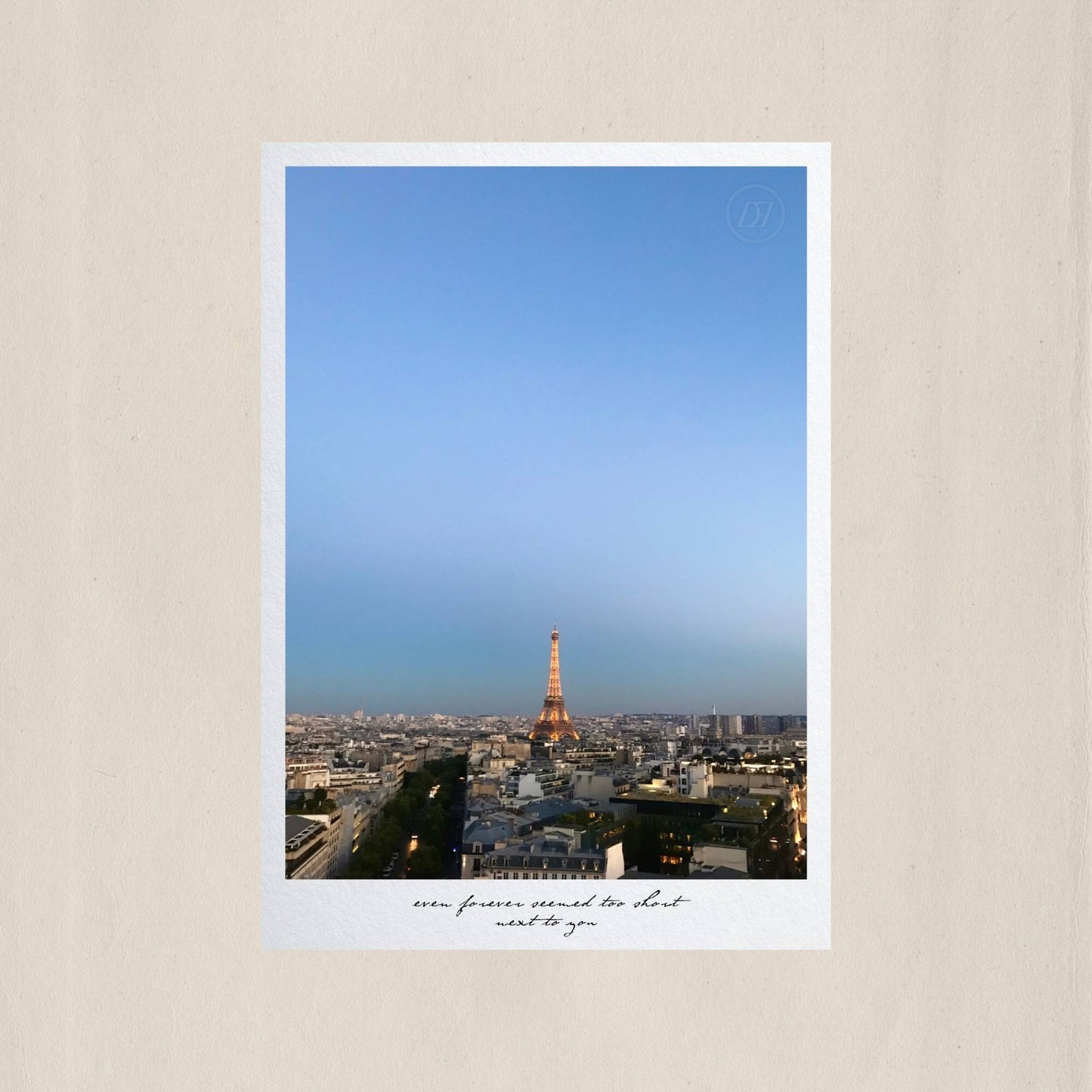 Paris stretching endlessly beneath a blue dusk sky, the illuminated Eiffel Tower glowing at the heart of it all – Des Épigraphes. Captured by Tolga Avan.