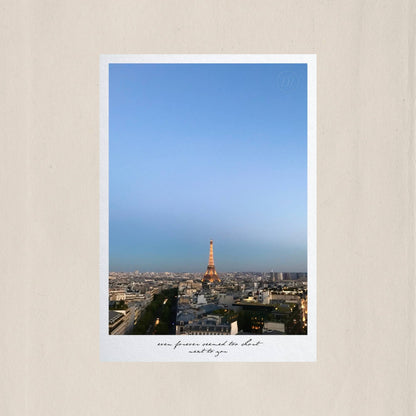 Paris stretching endlessly beneath a blue dusk sky, the illuminated Eiffel Tower glowing at the heart of it all – Des Épigraphes. Captured by Tolga Avan.